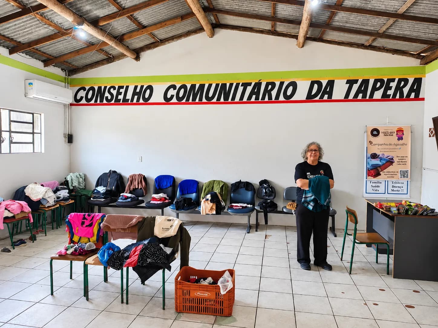 Voluntária da Associação Nós na Rua organizando doações de roupas no Conselho Comunitário da Tapera, em São José.